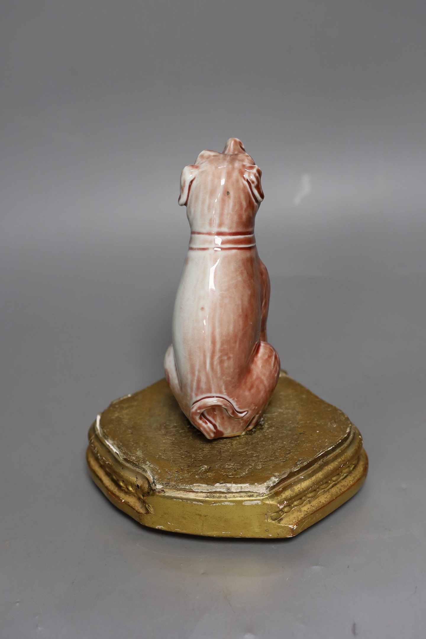 A Chinese porcelain model of a seated dog on gilt wood stand, 19cm tall